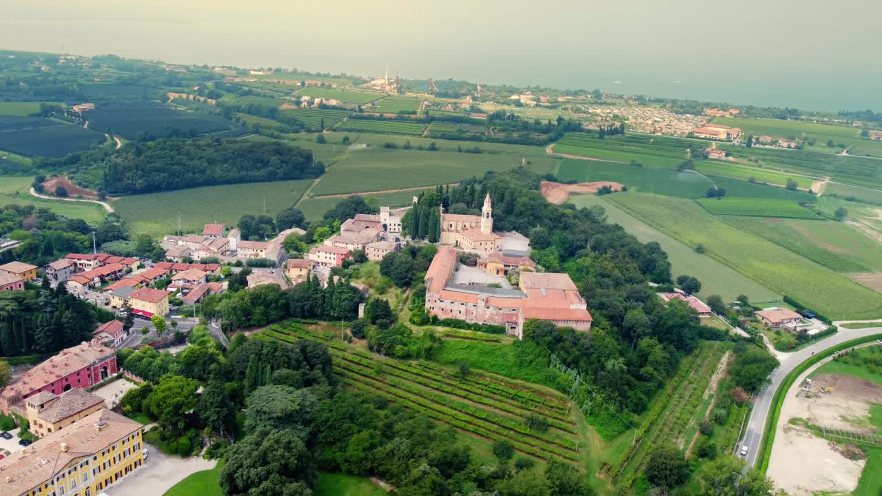 Aerial view of Colà di Lazise, a peaceful Italian village near Lake Garda, surrounded by vineyards, historic buildings, and rolling countryside in the Verona wine region.