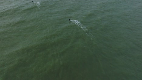 Establecimiento-De-Una-Vista-Aérea-De-Un-Grupo-De-Personas-Dedicadas-Al-Kitesurf,-Día-De-Invierno-Nublado,-Olas-Altas,-Deporte-Extremo,-Playa-De-Karosta-Del-Mar-Báltico,-Tiro-De-Drones-De-Ojo-De-Pájaro-Avanzando