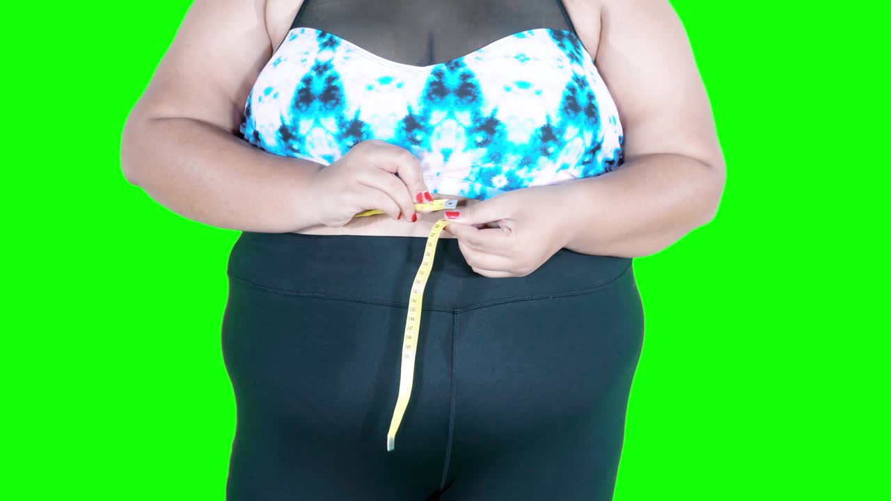 Closeup of overweight woman measuring waist
