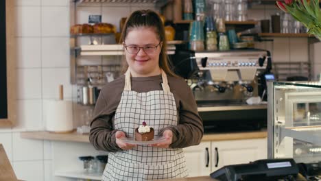 portrait of down syndrome girl as a worker in the cafe who is holding a piece of cake