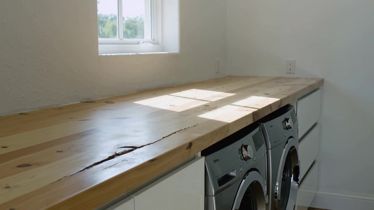 Panoramica della telecamera che rivela un bancone in legno massello e una lavatrice e asciugatrice argentate a casa per mostrare una crepa.