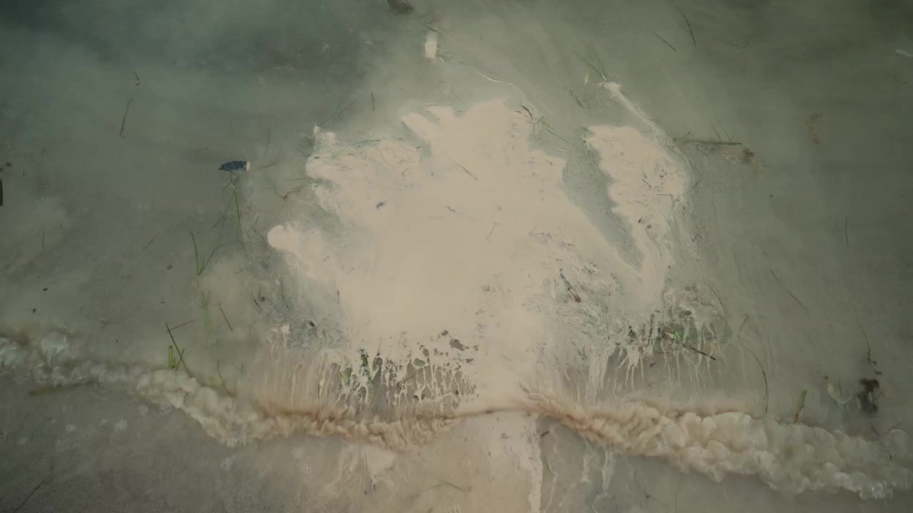 Schaumige Welle des Mittelmeers, die an einen Sandstrand spült