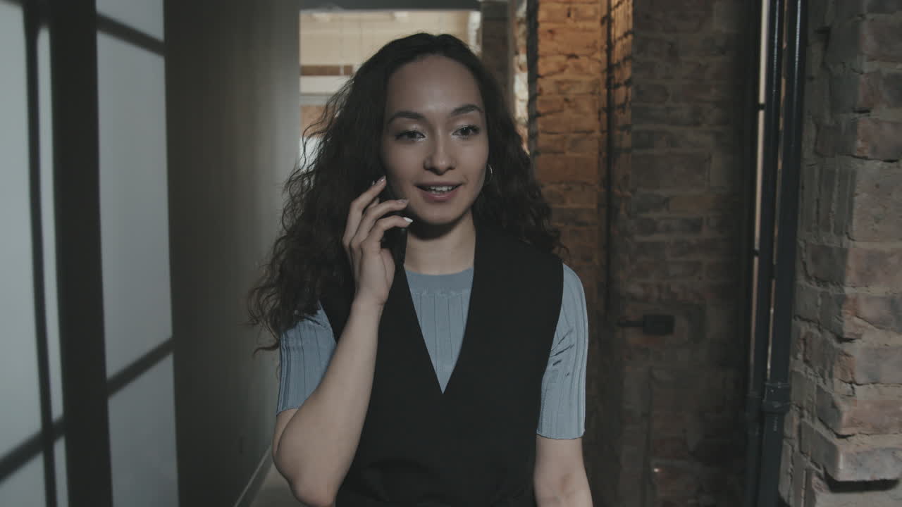 Giovane donna d'affari sicura di sé che cammina mentre parla al telefono