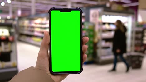 4k chroma key. close up of woman hand holds smart phone with green screen at shopping mall store. shopping center. department store. shopping online. gadgets template