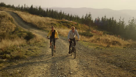 pareja en bicicletas montando en un camino de montaña. biciclistas felices entrenando al aire libre