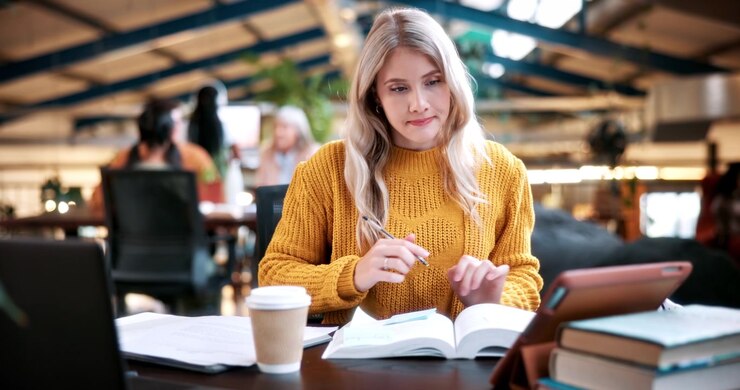 Ung kvinde studerer med tablet og bog på et moderne kontor