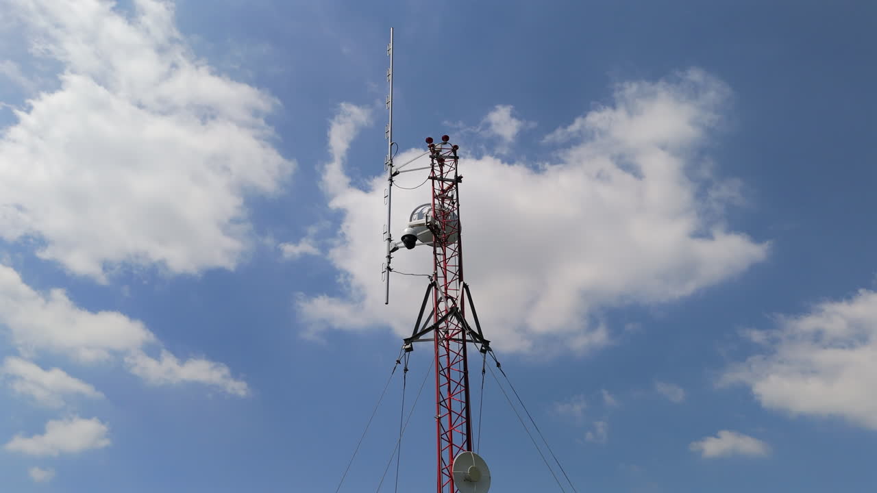 Tall communication tower standing against the sky, essential for signal transmission, aerial orbit with cloudy blue sky backdrop