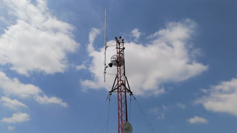 tall communication tower standing against the sky, essential for signal transmission, aerial orbit with cloudy blue sky backdrop