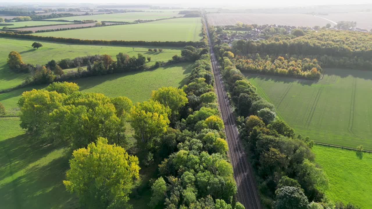 vía de tren entre dos líneas de vibrantes árboles de colores otoñales en la campiña de kent, cerca de canterbury
