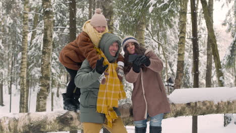 Father,-Mother-And-Daughter-In-Winter-Clothes-Taking-A-Selfie-In-The-Snowy-Forest