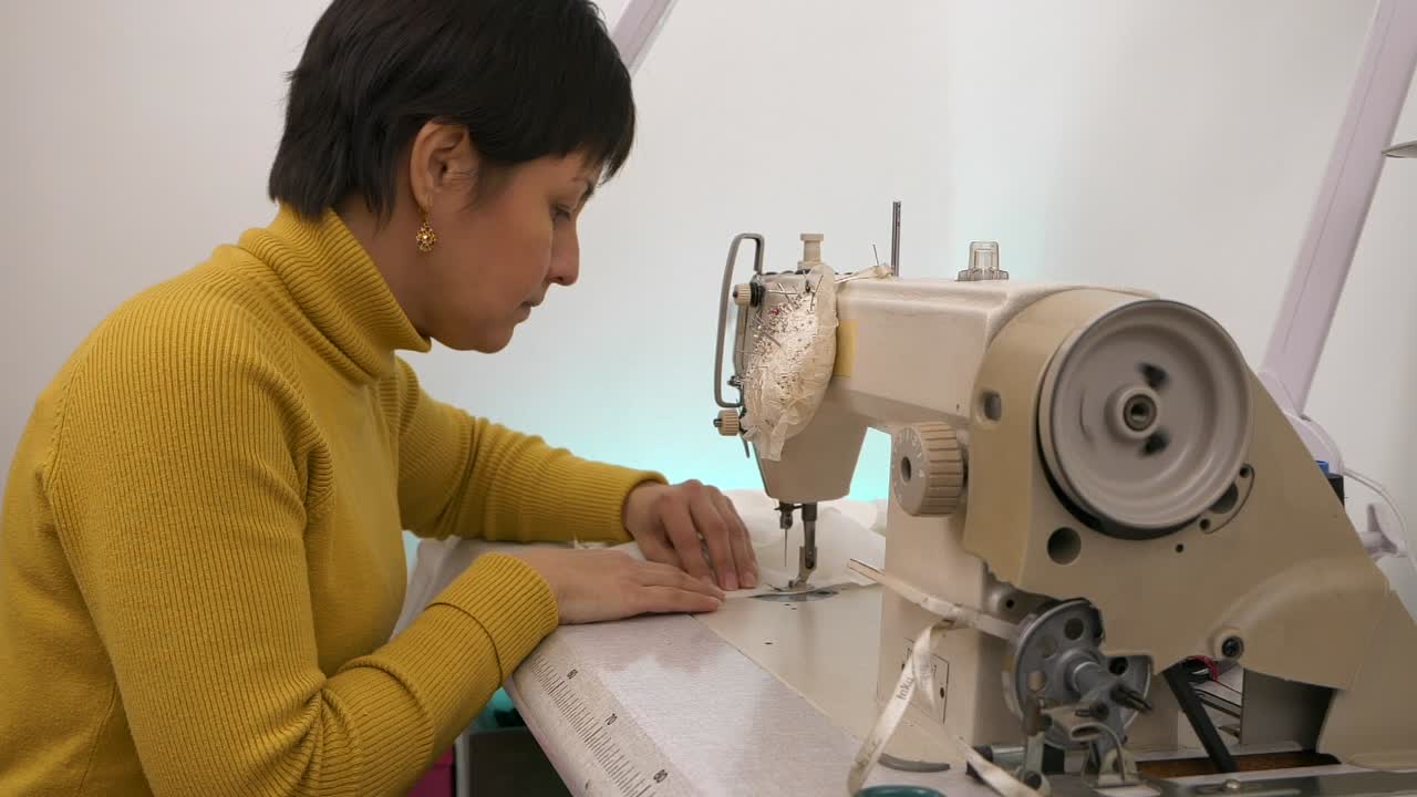 Wanita bekerja dengan mesin jahit profesional. Gerak lambat.