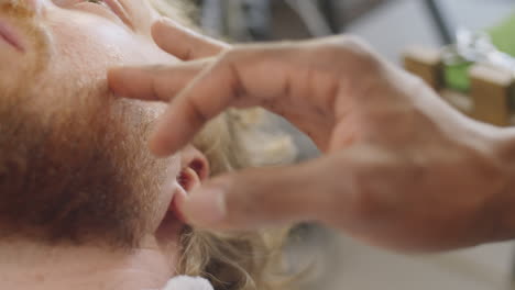 barber applying lotion to skin of client after shaving