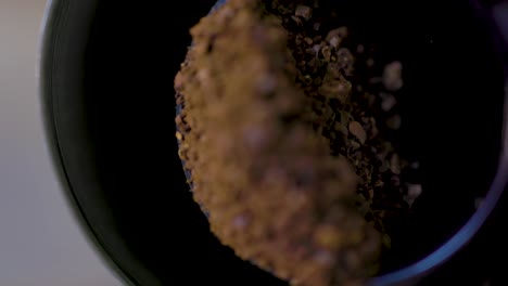 macro shot of grounded coffee beans in a grinder being scooped up to prepare a delicious coffee drink in the morning time for breakfast