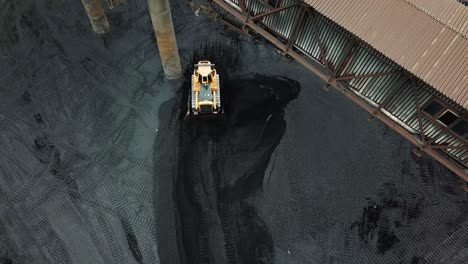 coal mining industry and transportation. yellow tractor riding at coal warehouse for transportation