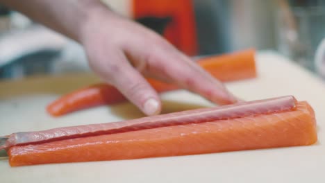 unrecognizable cook cutting raw salmon