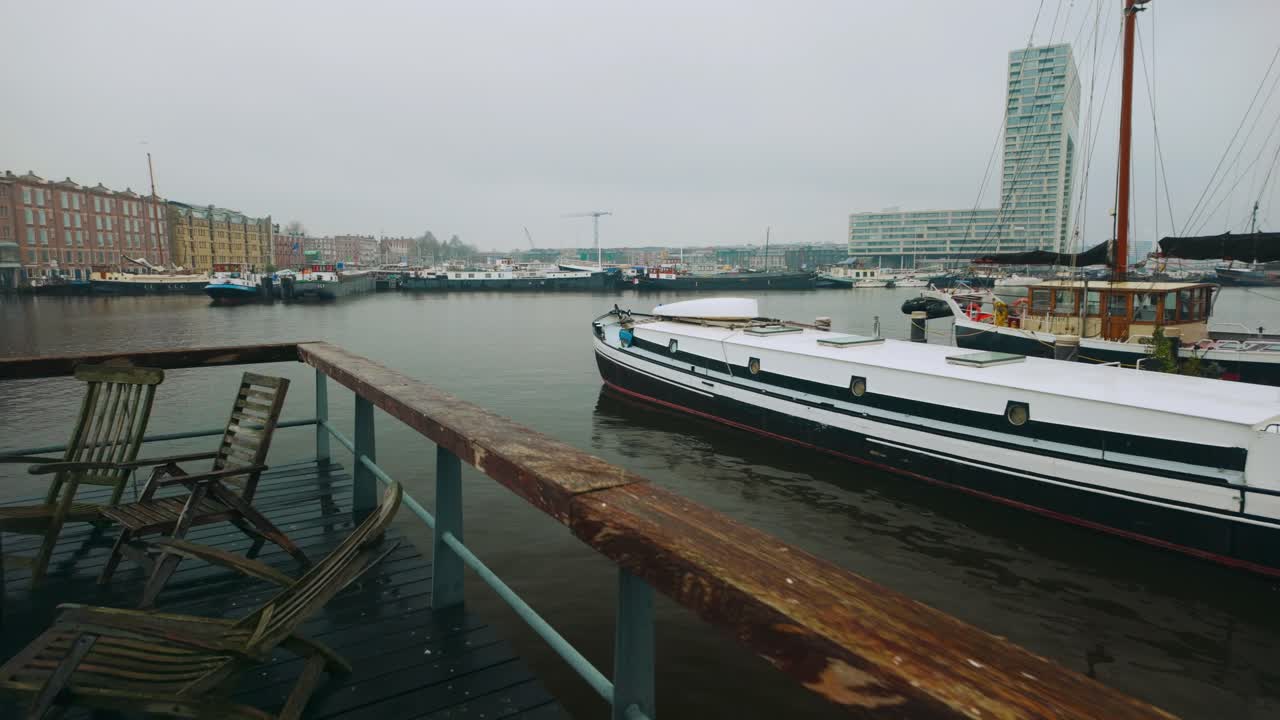 terraza con sillas de madera y barco de casa en el puerto del muelle de ámsterdam en invierno