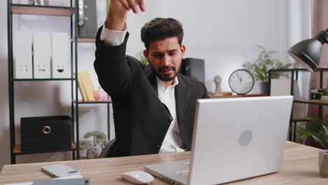 Hombre-De-Negocios-Trabajando-En-Una-Computadora-Portátil-De-Oficina-Apuntando-A-La-Cámara-Mirando-Con-Expresión-Feliz-Haciendo-Elecciones