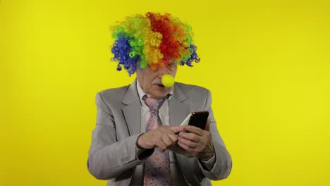 el payaso empresario independiente pierde dinero mientras juega juegos en línea en el teléfono