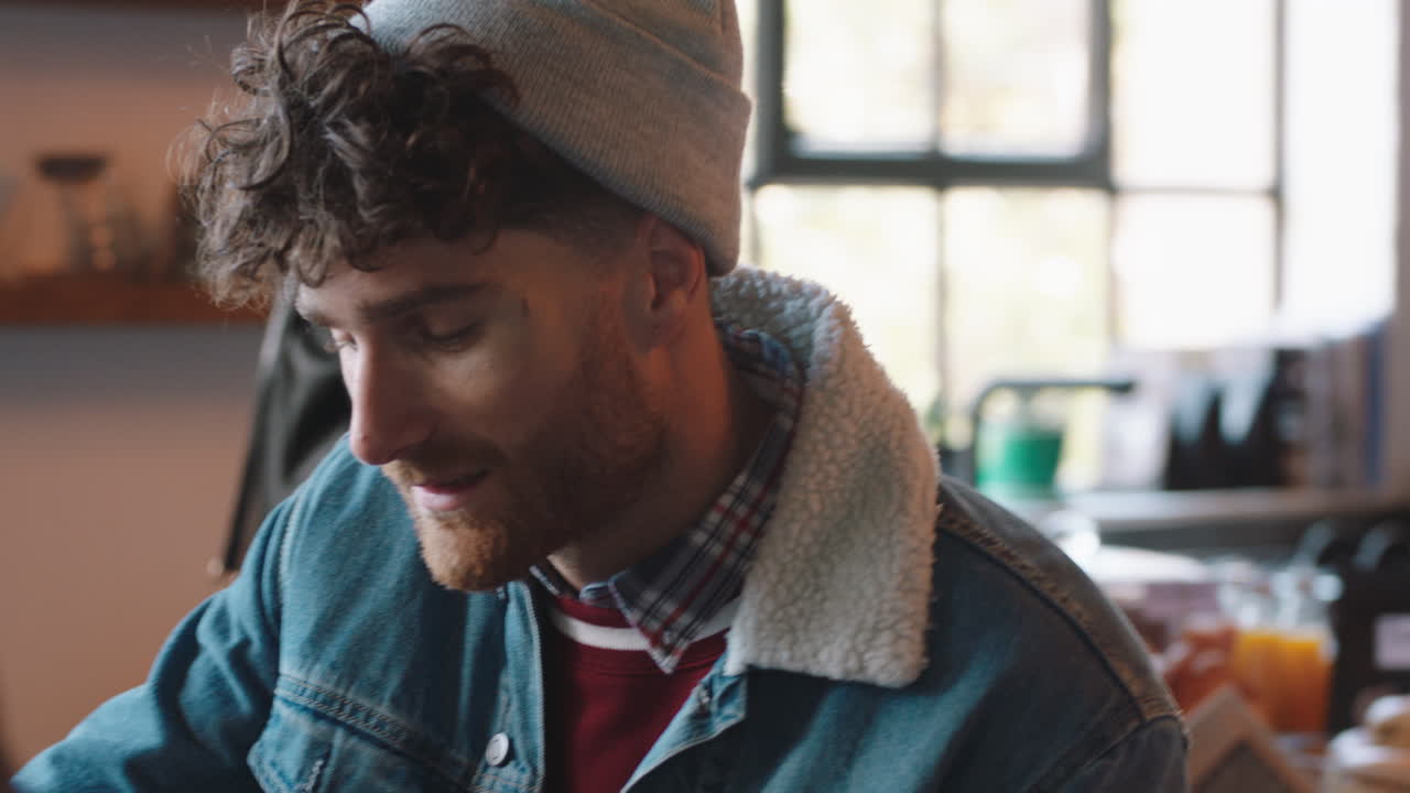 atractivo hombre hipster charlando con un amigo bebiendo café en un café disfrutando de la conversación relajándose en un restaurante ocupado