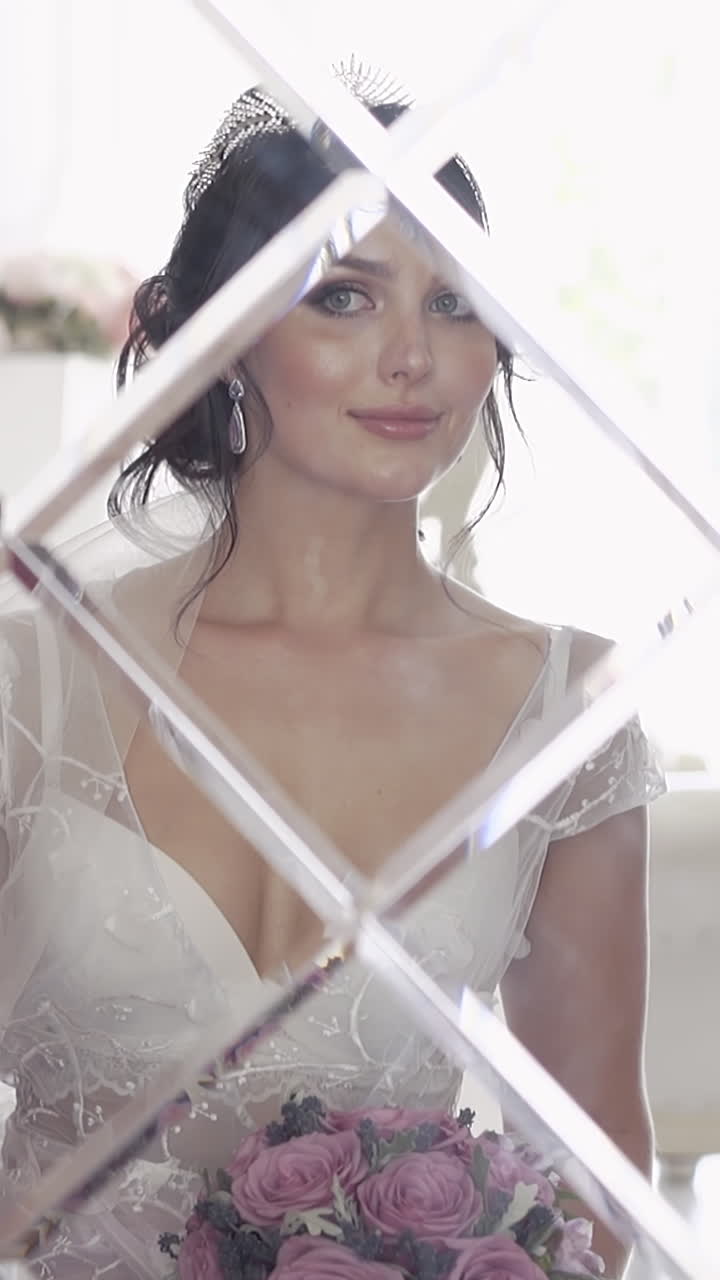 Hermosa dama con vestido de novia y ramo morado sentada en un gran sillón rojo, mirándose al espejo en cámara lenta