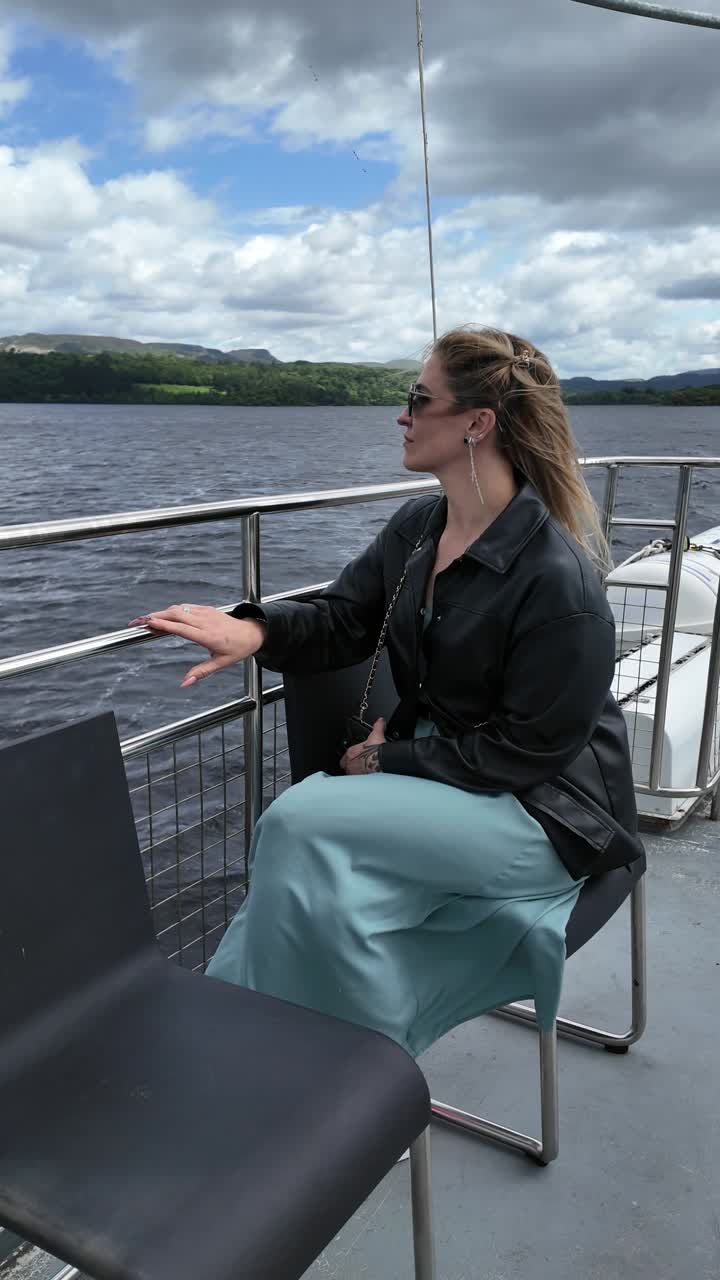Woman on tour boat enjoys the scenic view of a lake and mountains