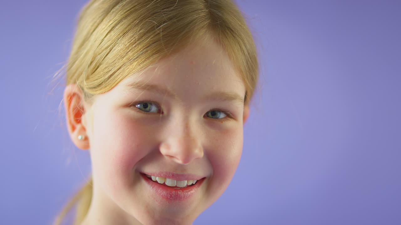 Studio Portrait Of Smiling Girl With Long Hair Against Purple Background