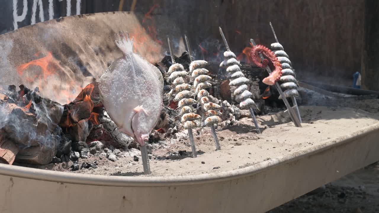 Assorted fish skewered and grilled over coals in a typical fishing boat on a beach in Málaga, Spain
