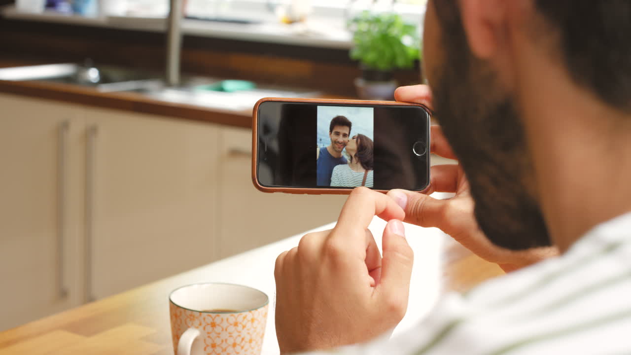 hombre mirando un teléfono con una foto de una pareja
