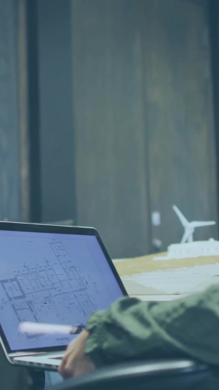 Architect Analyzing Blueprints on Laptop with Animated Data and World Map