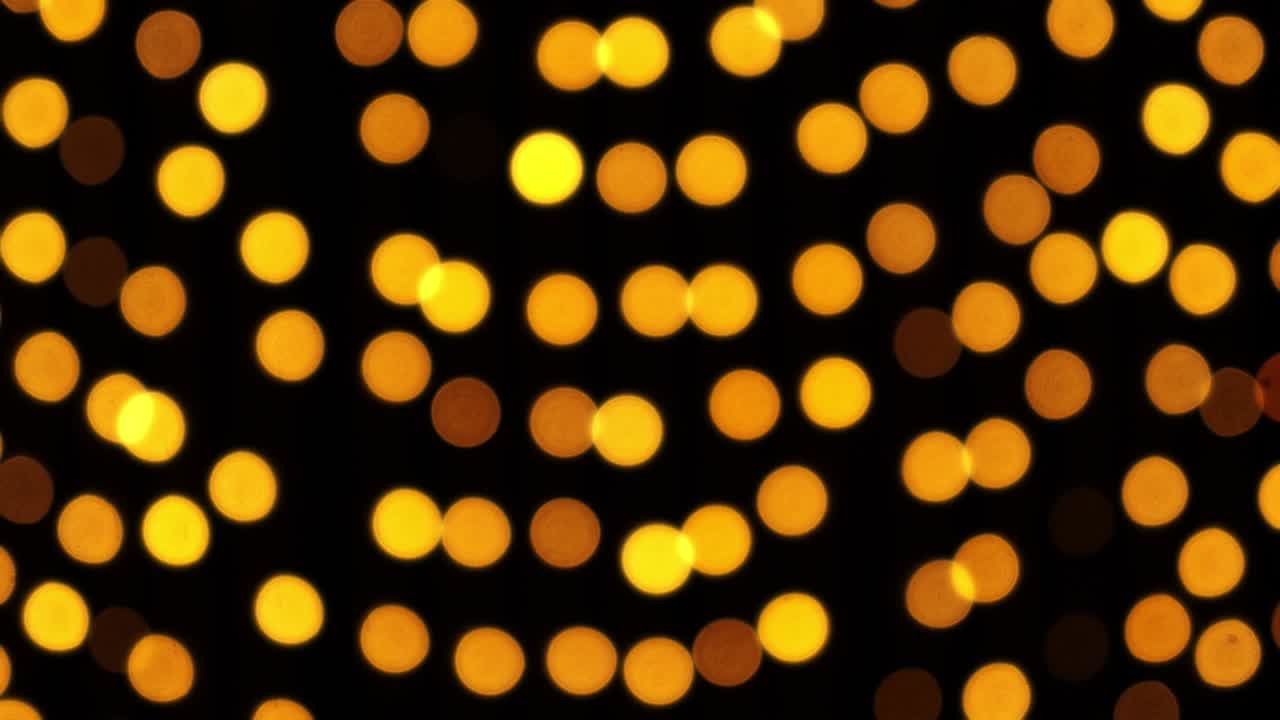 Abstract bokeh background in motion. shining, blurred golden particles, lights. bright bokeh from garlands on dark background. New year or Christmas festive backdrop