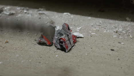 a man adjusts the coals on the concrete in front of the fireplace