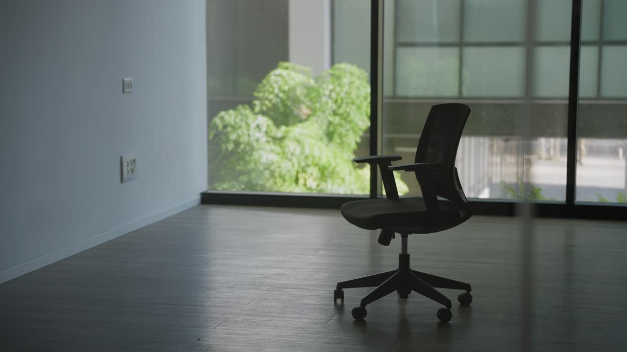 Modern empty and vacant office space with one wheeled chair in middle of room. Big glass windows in luxury building. Abandoned office or foreclosure going of business. Brand new company moving in