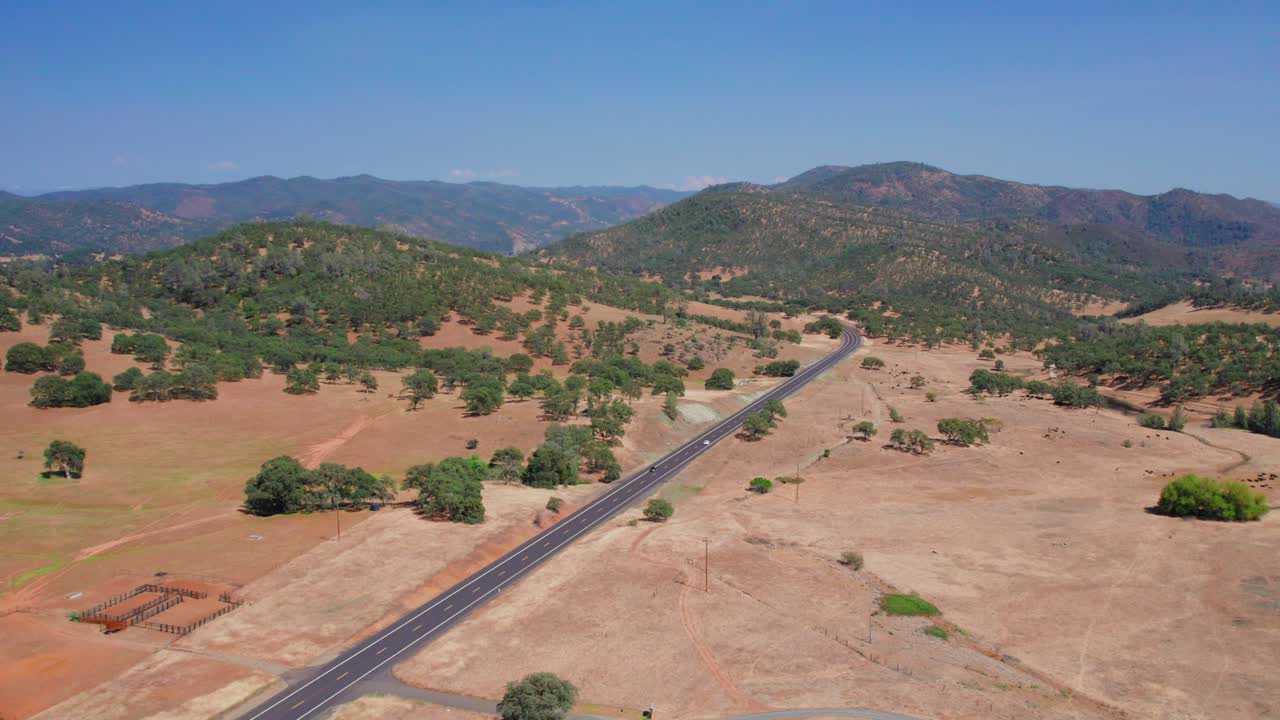 캘리포니아의 화창한 날 길고 탁 트인 도로에서 운전하는 자동차의 공중 패닝 드론 샷