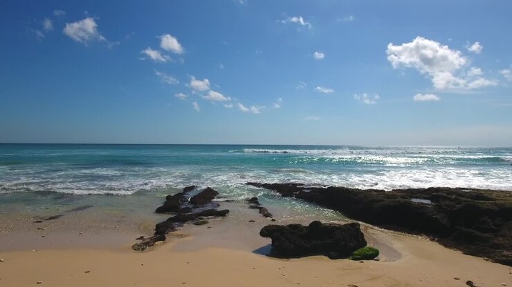 photo statique de la plage de bali avec un ciel bleu ensoleillé et quelques nuages moelleux, belle ligne de côte tropicale d'uluwatu, vue de vacances en indonésie