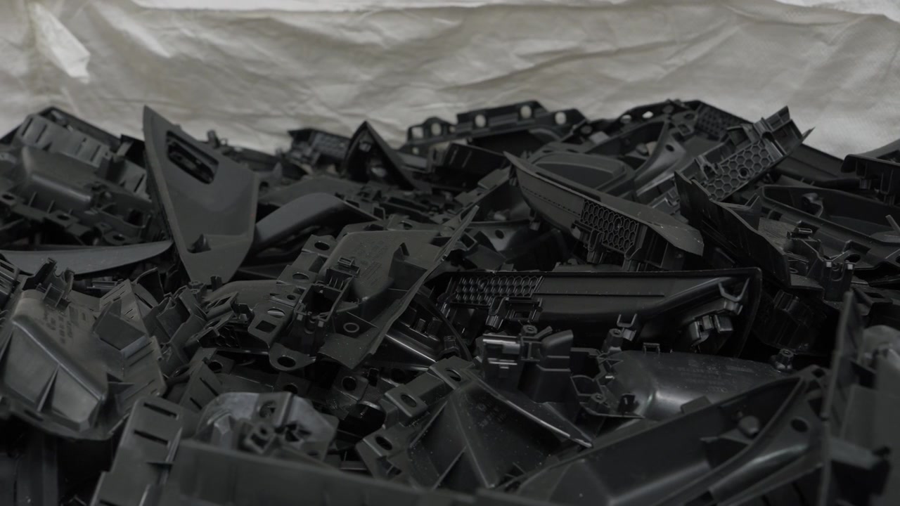 Pila di rottami automobilistici in plastica nera raccolti per il riciclaggio.