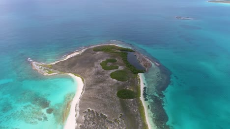 Aerial-tropical-island-with-lagoon-surrounded-by-turquoise-sea-water,-los-roques-archipelago,-pan-right