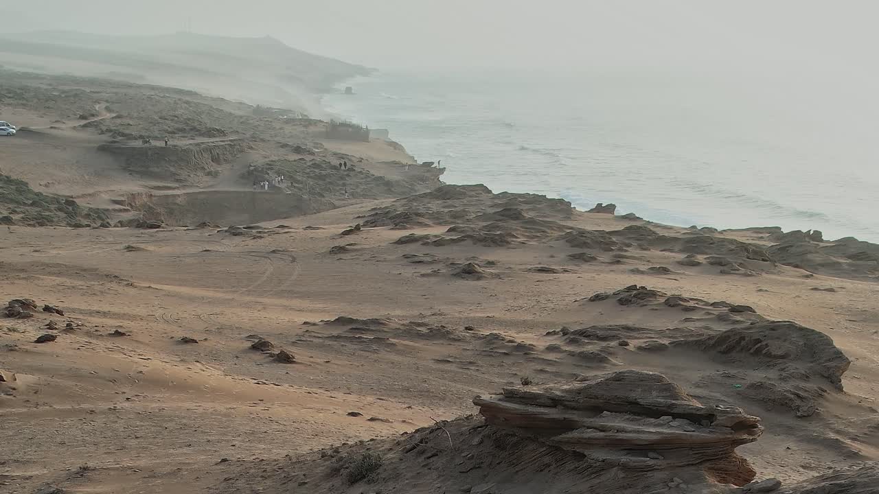Aerial view of coastline in Morocco with sandy terrain and vehicles nearby