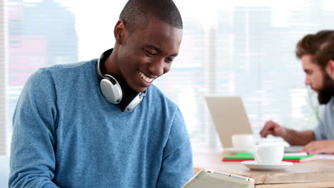 Un-Hombre-De-Negocios-Informal-Sonriente-Usando-Una-Tableta-Frente-A-Un-Colega