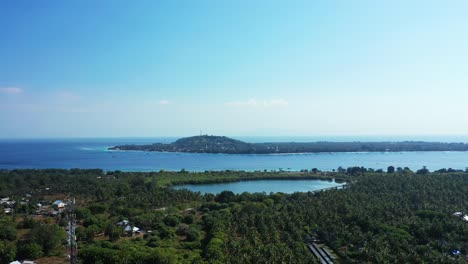 Large-tropical-Gili-islands-with-palm-trees-forest,-village's-houses-and-resorts-for-tourists-surrounded-by-blue-sea-under-clear-bright-sky