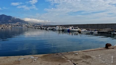 Water-reflects-stunning-blue-sky-with-view-of-mountains-and-boat-harbor