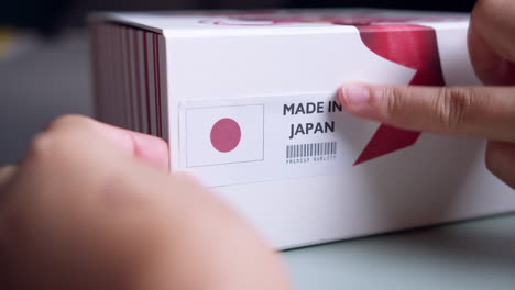 hands applying made in japan flag label on a shipping cardboard box with products