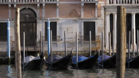 Góndolas-Negras-Vacías-Balanceándose-En-Un-Muelle-Cerca-De-La-Hermosa-Fachada-Blanca