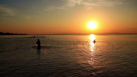 idyllic summer scene of people silhouettes swimming and enjoying the sea and sunset in koh sdach island cambodia, popular tourist destination