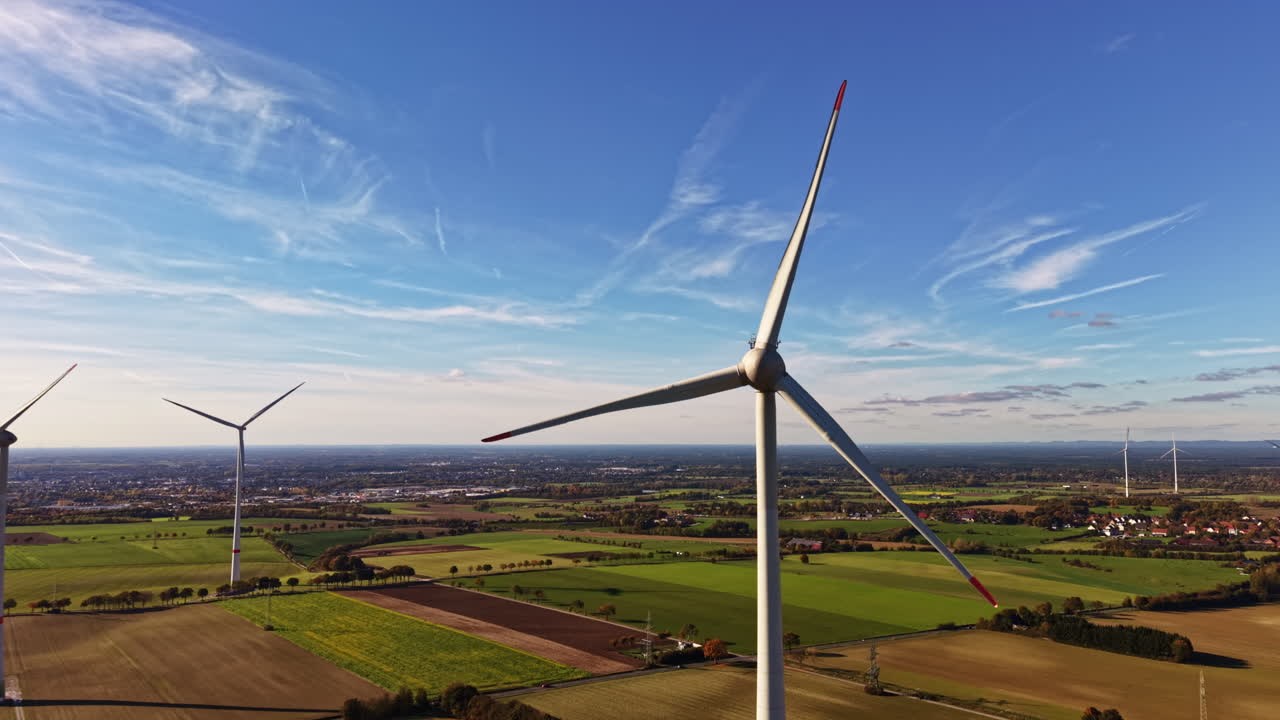 Wind turbines stand tall against a clear blue sky in the countryside showcasing renewable energy production in a vibrant landscape dotted with fields and farms