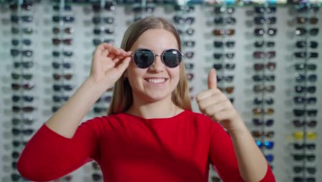portrait of a girl in stylish sunglasses indoors. beautiful young woman wearing fashionable black glasses on the background of optical store.