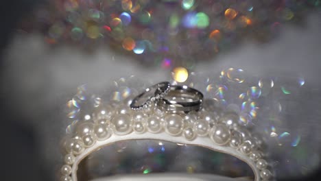 silver wedding rings on a pearl display with shiny diamond background