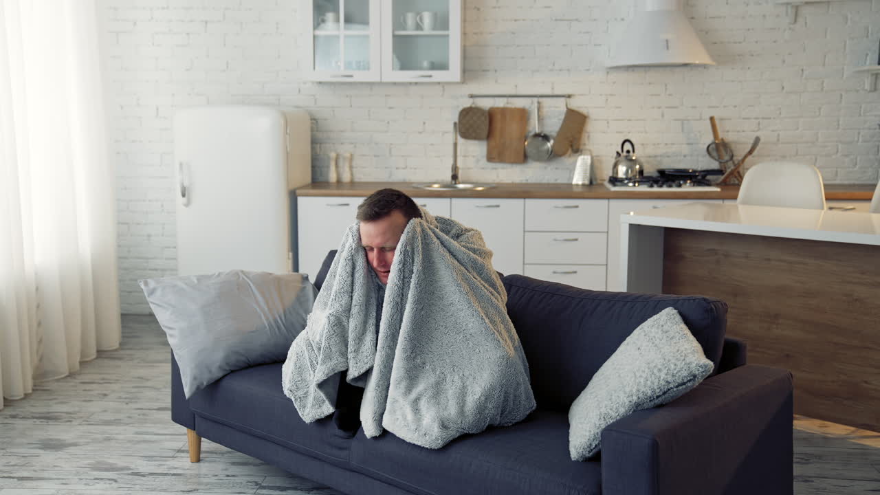 Sick young man suffering from flu at home. Pandemic. Quarantine concept.