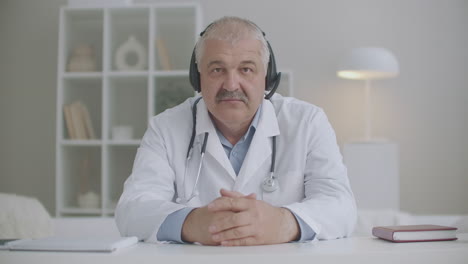 doctor is nodding and looking at camera of notebook during online consultation using headphones for listening patient telemedicine service