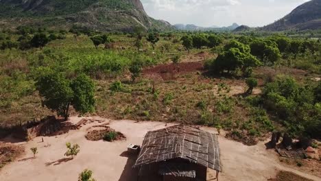 Aerial drone shot descending toward an isolated rural hut in Mozambique, surrounded by farmland