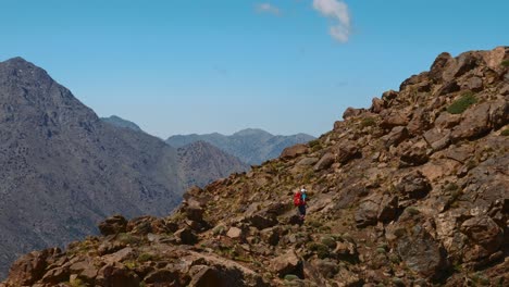 turista de mochila que asciende en el terreno rocoso de las altas montañas del atlas